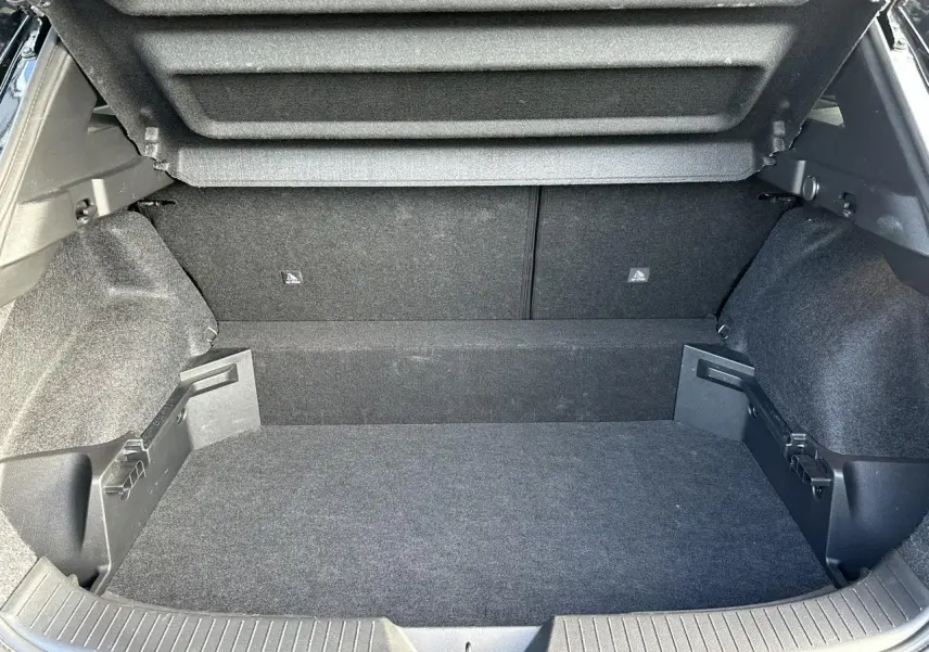 Coffre ouvert vu de l'arrière d'un Nissan Qashqai blanc nacré, montrant l'espace de chargement vide et le hayon relevé.
