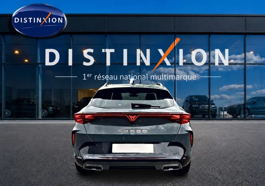 Vue arrière d'une CUPRA Formentor bleu fjord 2026 avec feux LED et double sortie d'échappement, devant un showroom Distinxion.