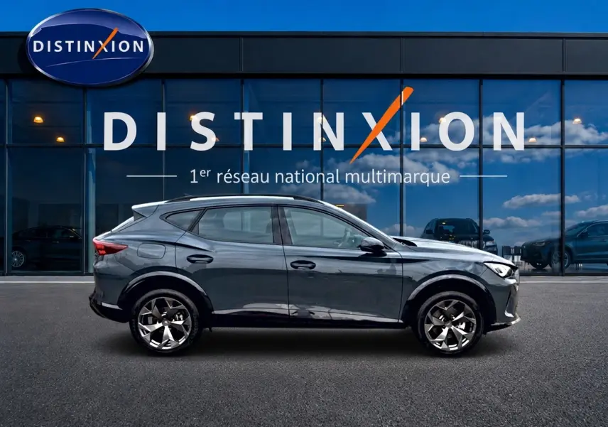 Vue latérale droite d’un CUPRA Formentor bleu fjord 2026 avec jantes 18 pouces devant une vitrine Distinxion.