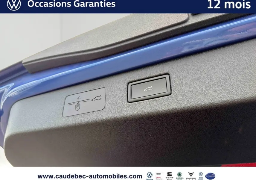 Bouton d'ouverture électrique du coffre sur la porte arrière d'un Volkswagen T-Roc bleu, vue en gros plan.