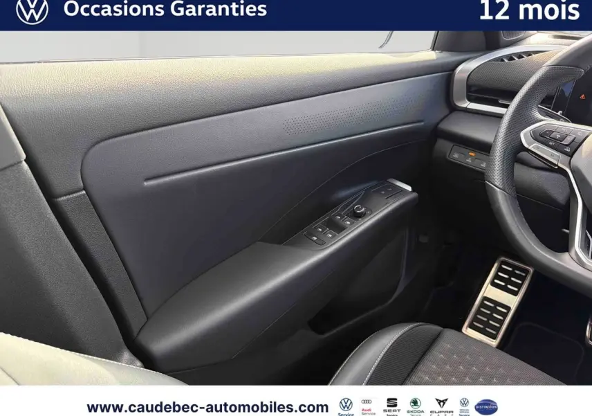 Vue intérieure côté conducteur du Volkswagen T-Roc 2026, montrant la portière noire avec commandes des vitres et partie du volant cuir.