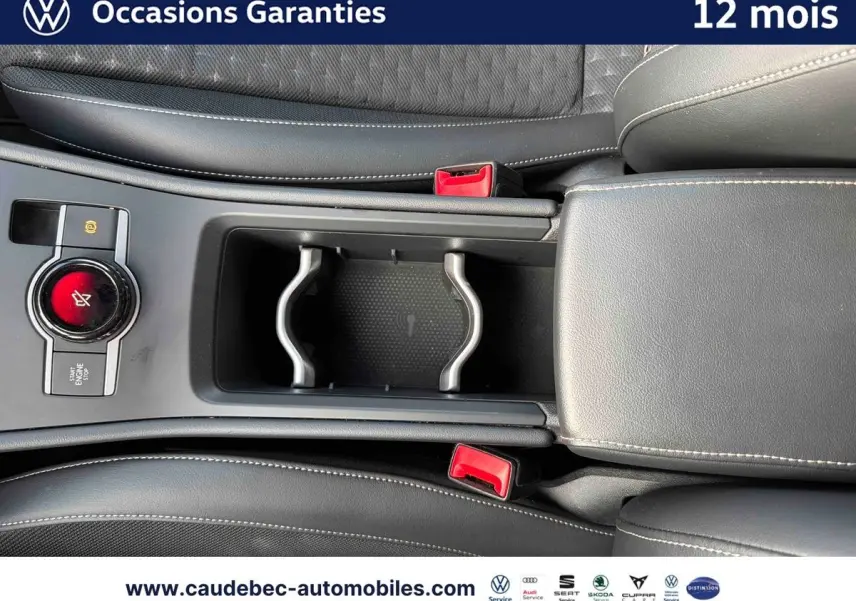 Vue rapprochée de la console centrale du Volkswagen T-Roc 2026, avec accoudoir cuir noir et bouton Start/Stop rouge.