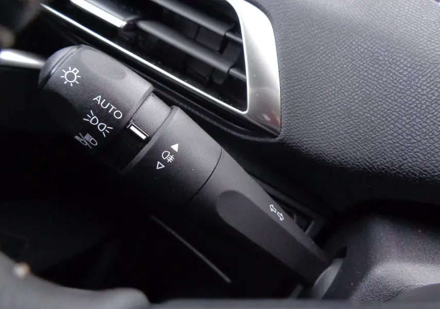 Gros plan sur la commande des phares et clignotants dans l'habitacle du Peugeot 3008 gris Artense 2023.