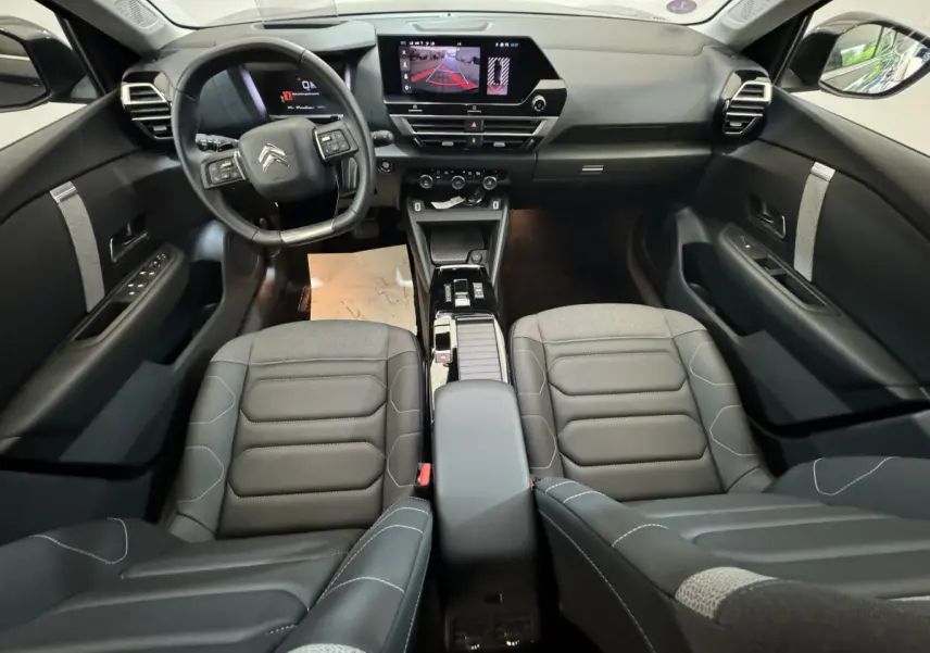 Intérieur noir de la Citroën C4 PureTech 130, vue avant centrée sur le tableau de bord et les sièges cuir.