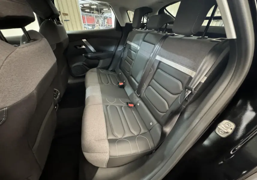 Vue côté gauche de l'habitacle arrière noir d'une Citroën C4 2023 avec sièges bi-matière cuir et tissu gris.