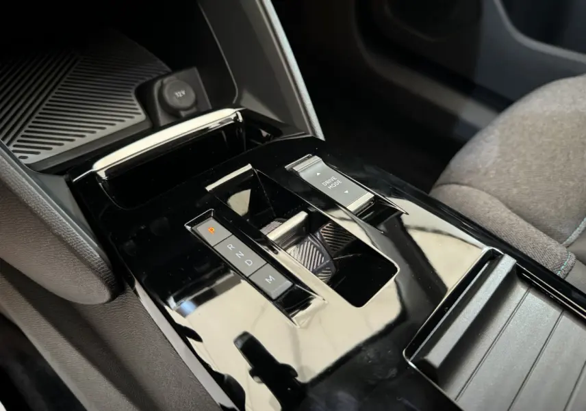 Gros plan sur la console centrale noire brillante de la Citroën C4 PureTech 130 EAT8 Shine avec sélecteur de boîte auto et commande Drive Mode.