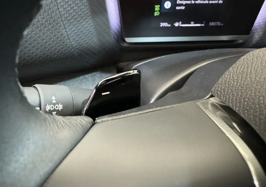 Gros plan sur la palette de changement de vitesses noire et le tableau de bord numérique d'une Citroën C4 PureTech 130 noire.