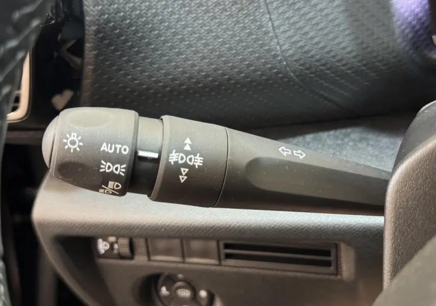 Gros plan sur la commande des phares et clignotants dans l'habitacle noir de la Citroën C4 PureTech 130 EAT8 Shine 2023.