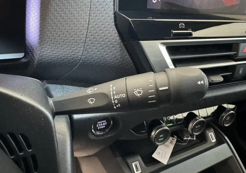Gros plan sur la commande d’essuie-glace et le bouton start/stop du tableau de bord noir de la Citroën C4 2023 Shine.