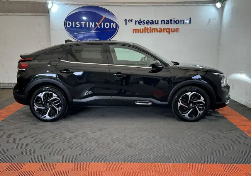 Profil côté gauche d'une Citroën C4 PureTech 130 EAT8 Shine noire, avec jantes alliage et toit noir en showroom.
