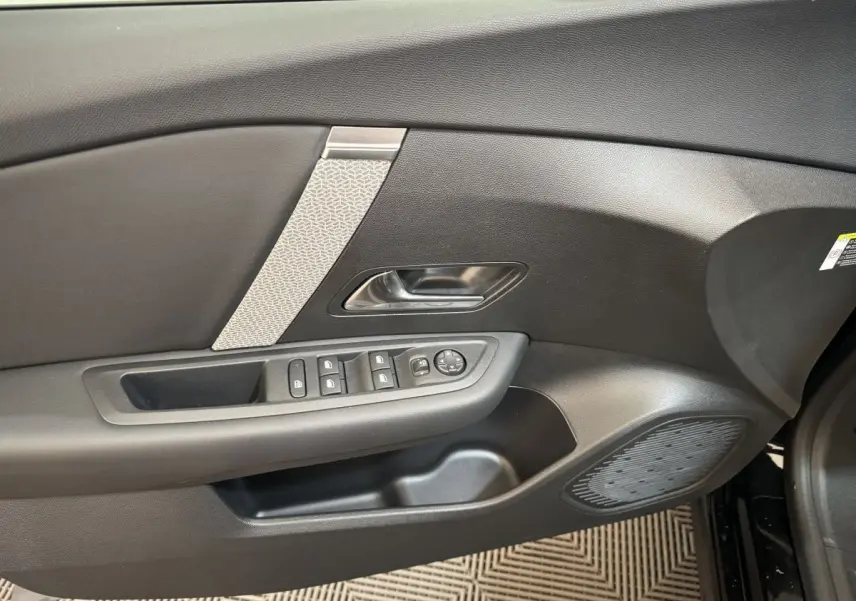 Vue du panneau de porte côté gauche noir de la Citroën C4 PureTech 130 EAT8 Shine avec commandes électriques et insert décoratif clair.