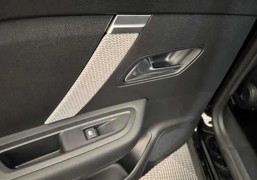 Gros plan sur la porte intérieure côté gauche noire avec poignée argentée et bouton de verrouillage fenêtre.