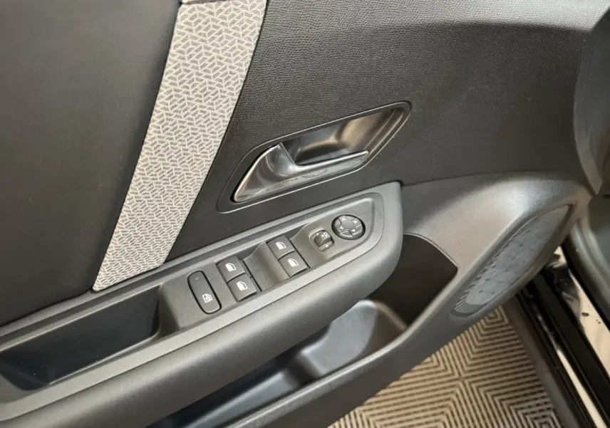 Vue rapprochée de la porte avant gauche noire du Citroën C4 2023 avec commandes électriques et insert décoratif gris.