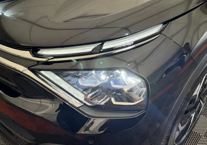 Gros plan sur le phare avant droit LED d'une Citroën C4 noire 2023, soulignant ses lignes modernes et détails chromés.