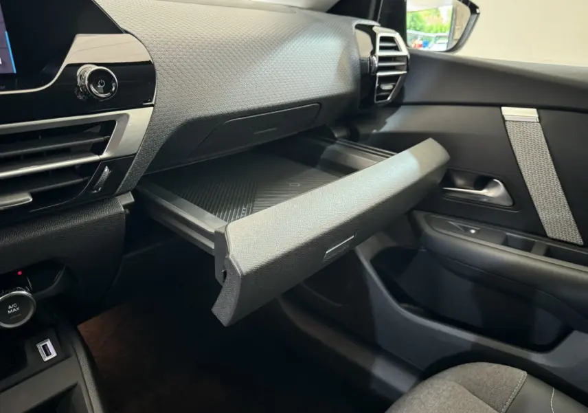 Intérieur de la Citroën C4 PureTech 130 noir, vue côté passager avec boîte à gants ouverte et tableau de bord texturé.