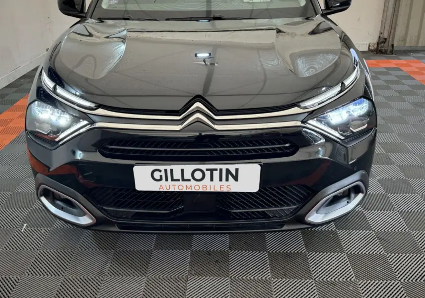 Vue avant d'une Citroën C4 PureTech 130 noire avec phares LED allumés et calandre chromée distinctive.