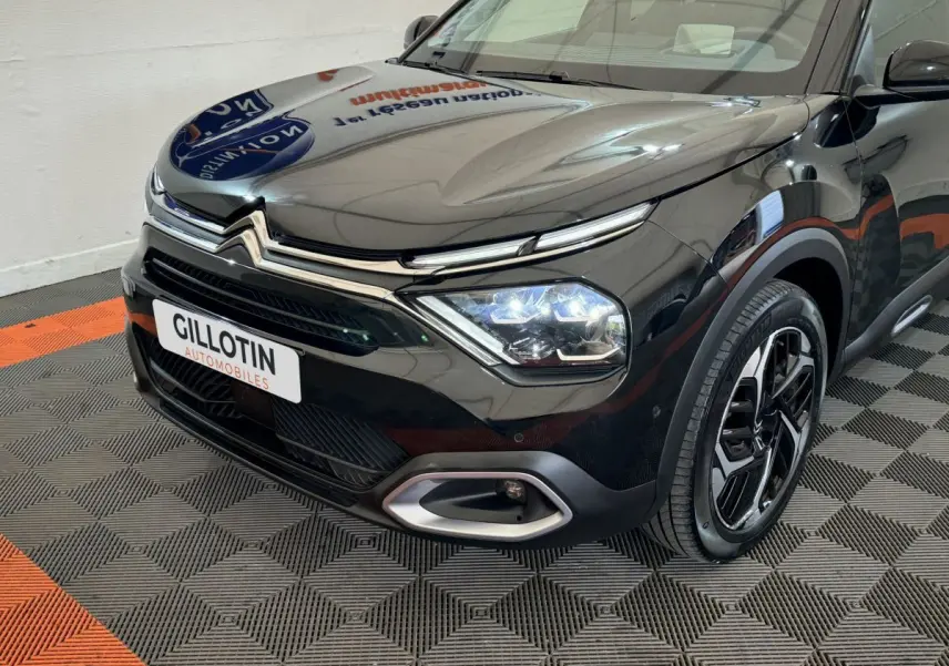 Vue 3/4 avant droit d'une Citroën C4 noire 2023 avec phares LED allumés et jantes alliage distinctives.