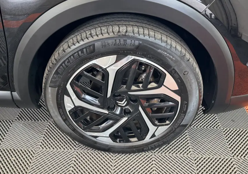 Gros plan sur la roue avant droite noire d'une Citroën C4 2023 avec jante en alliage au design moderne.