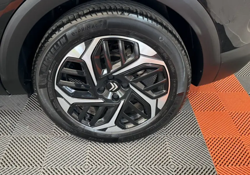 Gros plan sur la roue avant droite noire de la Citroën C4 PureTech 130 EAT8 Shine avec jante alu bicolore design.