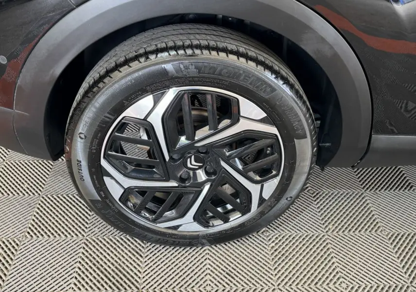 Gros plan sur la roue avant droite noire d'une Citroën C4 PureTech 130 EAT8 Shine avec jante alliage bicolore.