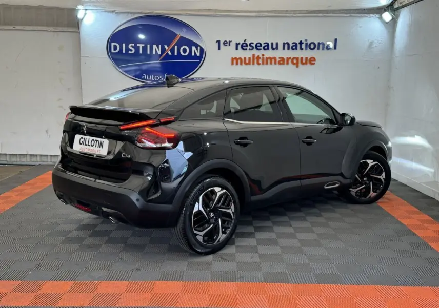 Citroën C4 noir vue 3/4 arrière droit en intérieur, avec feux arrière LED et jantes distinctives.