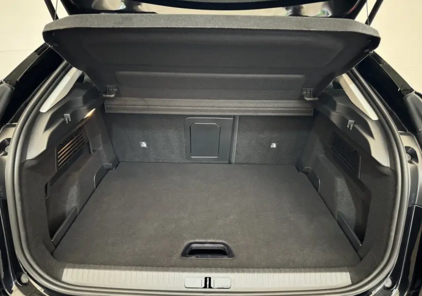 Coffre ouvert vu de l'arrière d'une Citroën C4 PureTech 130 noire, espace de chargement propre et spacieux.