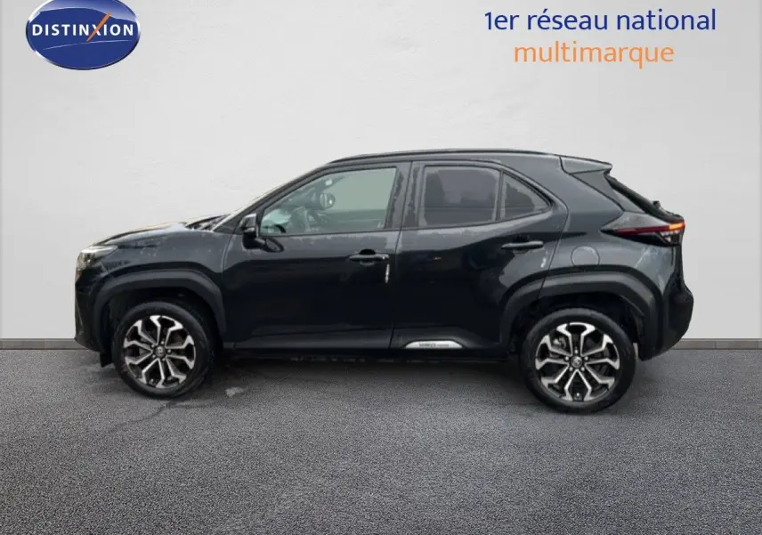 Profil côté gauche de la Toyota Yaris Cross 116h Design noire 2023 avec jantes bi-ton et lignes modernes distinctives.