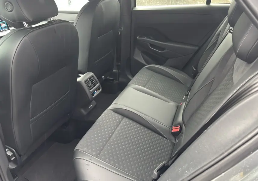 Vue intérieure arrière droite du Volkswagen T-Roc 2026, sièges tissu et cuir gris avec surpiqûres blanches.