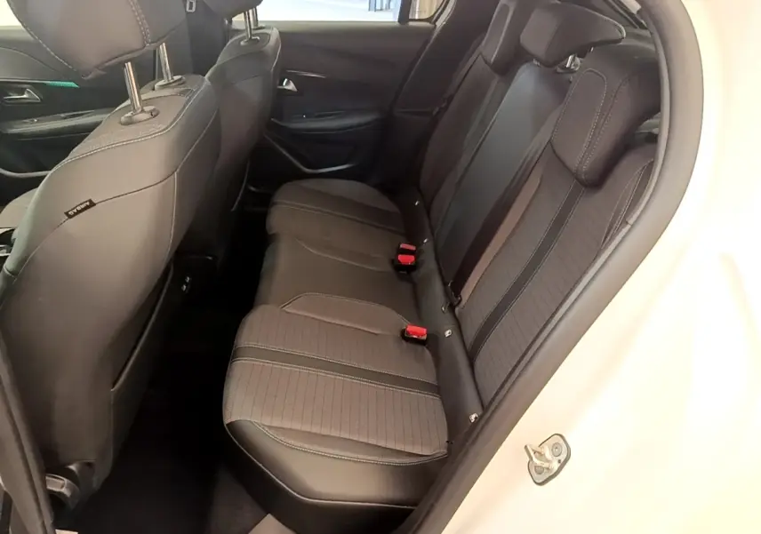 Vue intérieure côté droit montrant la banquette arrière noire et grise du Peugeot 208 blanc, avec ceintures rouges visibles.