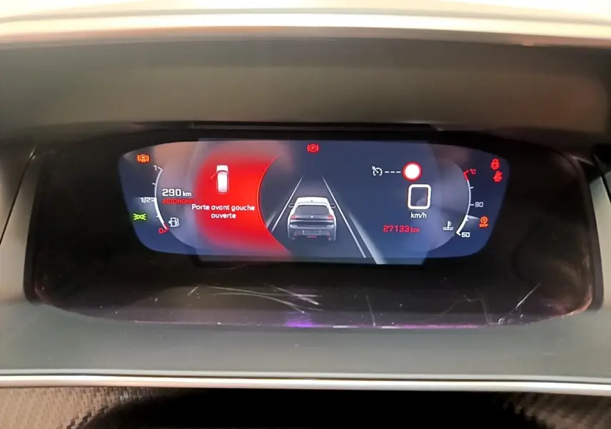 Vue rapprochée du tableau de bord numérique de la Peugeot 208 blanc, affichant une porte avant gauche ouverte et 27 193 km au compteur.