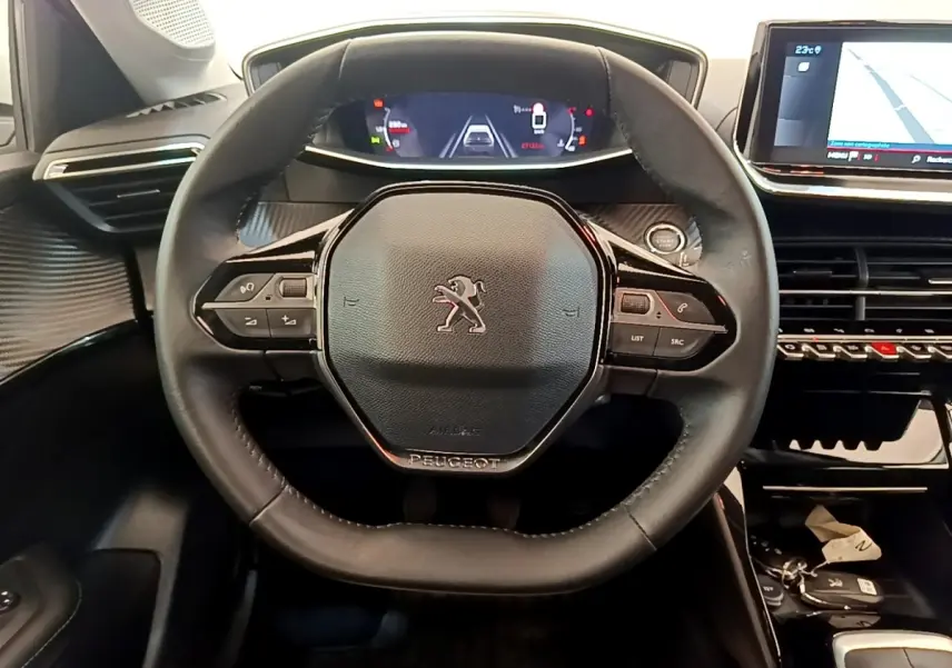 Vue intérieure centrée sur le volant cuir noir de la Peugeot 208 avec tableau de bord numérique et écran tactile de navigation.