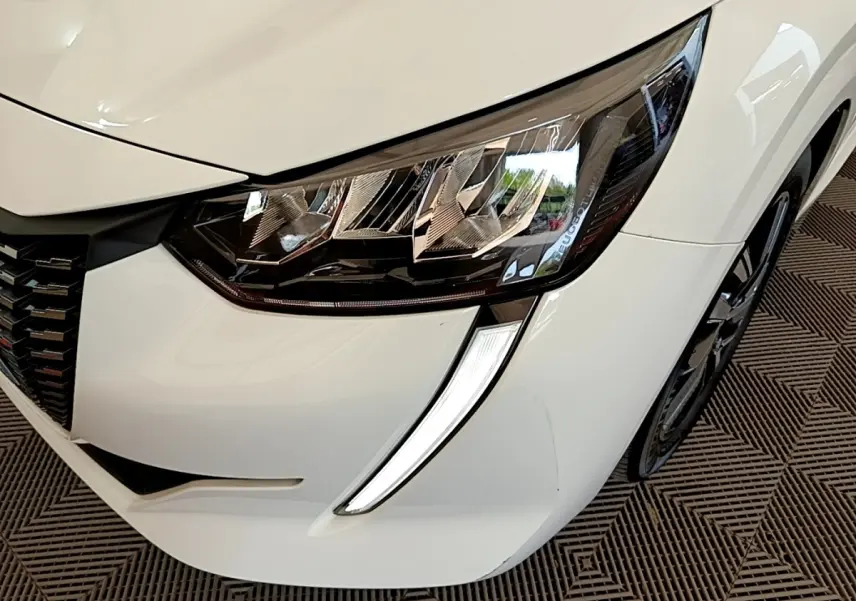 Gros plan sur le phare avant droit blanc du Peugeot 208 avec sa signature lumineuse LED distinctive.