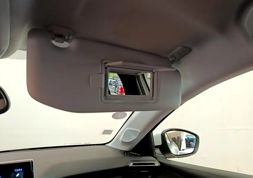 Intérieur du Peugeot 208 blanc, vue côté droit sur pare-soleil avec miroir et rétroviseur extérieur.