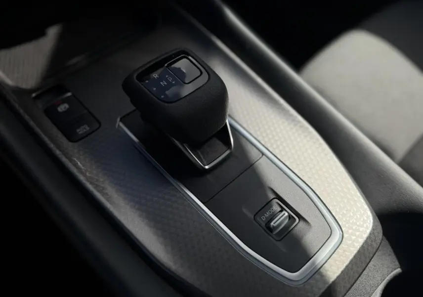 Gros plan sur la console centrale avec levier de boîte automatique et bouton D-Mode du Nissan Qashqai blanc nacré 2025.