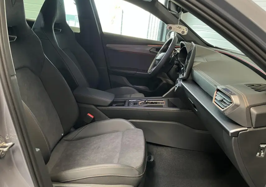 Vue intérieure côté conducteur du CUPRA Formentor gris clair 2025, sièges sport noirs avec surpiqûres cuivrées et tableau de bord moderne.