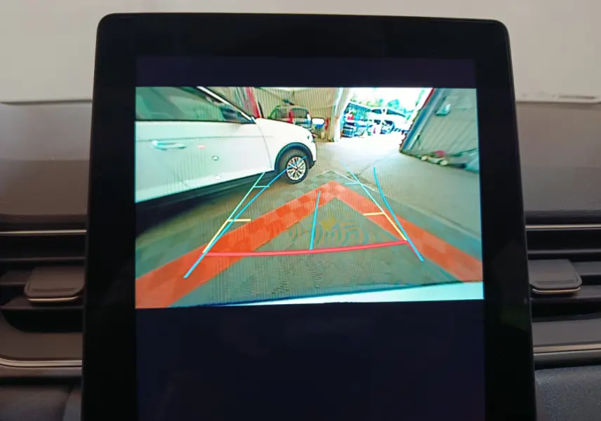 Vue écran caméra de recul montrant un Renault Captur blanc garé côté gauche dans un garage.