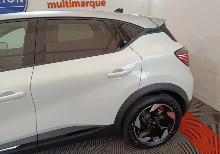 Vue latérale côté droit du Renault Captur blanc 2025, mettant en valeur la porte arrière et la roue arrière au design moderne.