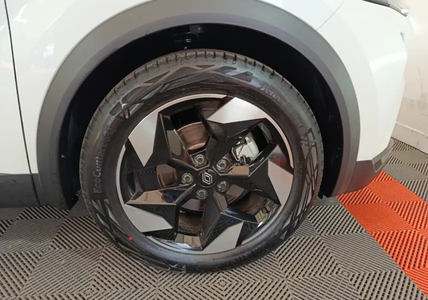 Gros plan sur la roue avant gauche du Renault Captur blanc, mettant en valeur la jante noire et argentée au design géométrique.