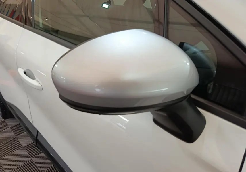 Rétroviseur côté gauche blanc du Renault Captur 2025 techno E-Tech hybride, avec poignée de porte visible en arrière-plan.