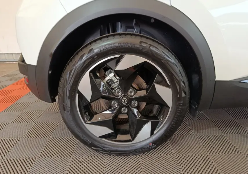 Gros plan sur la roue avant droite blanche du Renault Captur 2025 avec jante noire et argent au design géométrique.