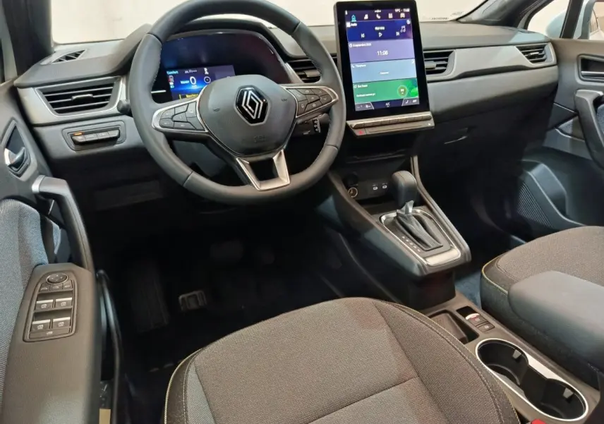 Intérieur Renault Captur 2025 vu côté conducteur, volant cuir, écran tactile vertical et console centrale noire.