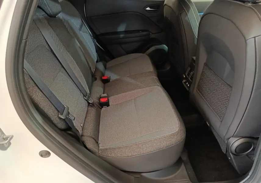 Vue côté gauche des sièges arrière gris foncé du Renault Captur blanc 2025, avec ceintures et poche de rangement au dos des sièges avant.