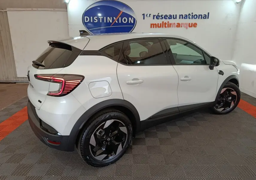 Renault Captur Techno E-Tech blanc vu de profil côté droit, avec jantes noires et feux arrière LED allumés.