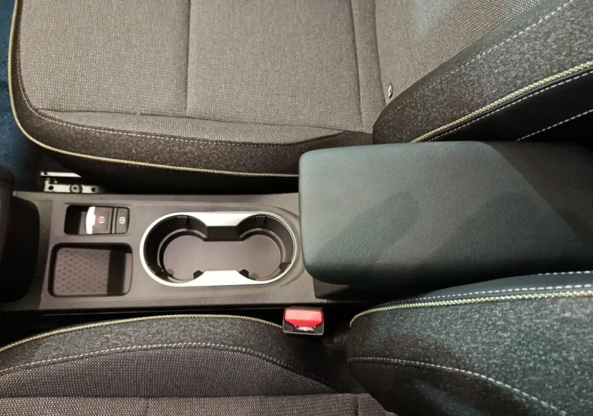 Vue plongeante sur la console centrale noire et les sièges gris foncé avec surpiqûres jaunes du Renault Captur blanc 2025.