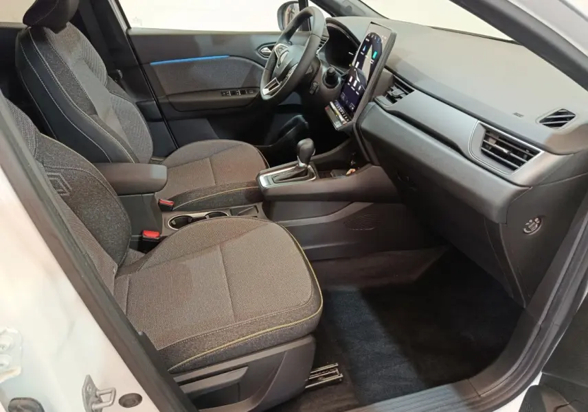 Intérieur avant droit du Renault Captur blanc 2025, sièges gris, écran tactile vertical et volant multifonctions.