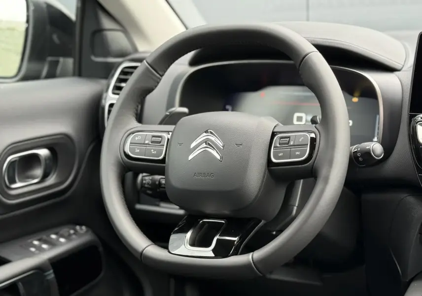 Vue rapprochée du volant cuir noir avec commandes intégrées du tableau de bord du Citroën C5 Aircross 2025.