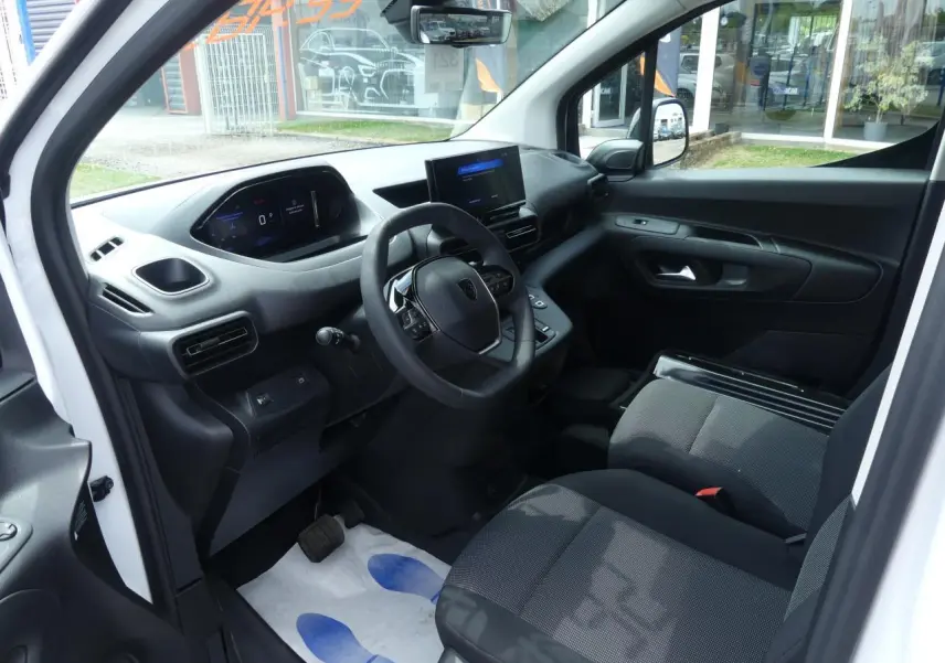 Vue intérieure côté conducteur du Peugeot Partner blanc 2025, avec tableau de bord numérique et écran tactile central.