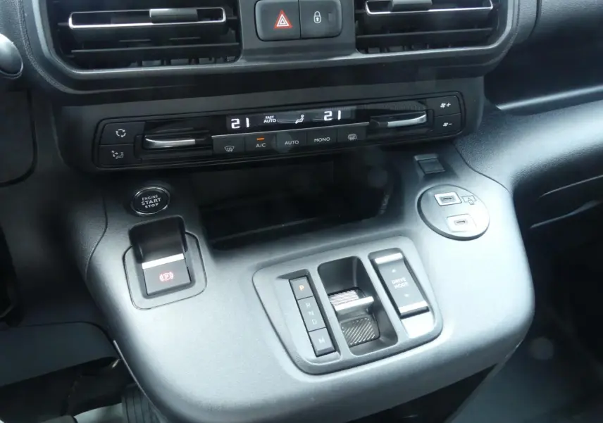 Gros plan sur la console centrale noire du Peugeot Partner 2025 avec commandes climatisation et boîte auto compacte.