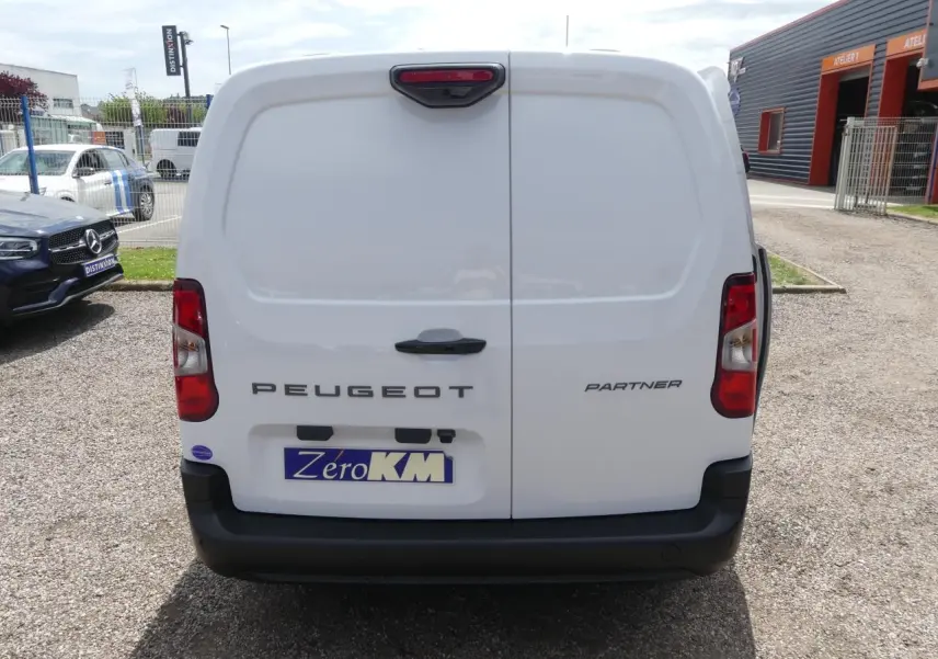 Vue arrière d'un utilitaire Peugeot Partner blanc avec portes battantes et pare-chocs noir mat.