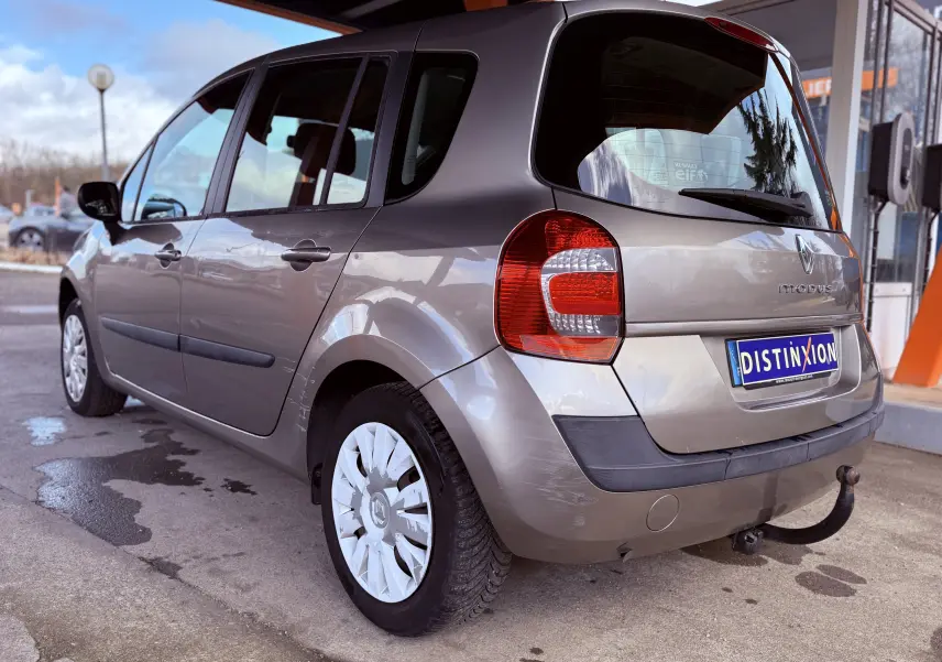Vue 3/4 arrière gauche d'une Renault Modus beige de 2011 avec attelage et jantes à enjoliveurs blancs.